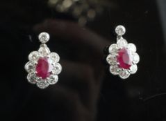 A pair of 18ct white gold, ruby and diamond cluster earrings, of oval form, with an approximate