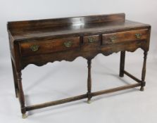 A late 18th century oak dresser base, fitted three drawers, over a shaped apron, with turned