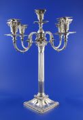 A late Victorian silver four branch five light corinthian column candelabrum, with reeded scroll