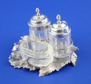 A Victorian silver cruet stand modelled as a leaf, with ring handle, two silver mounted bottles and