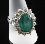 A 14ct white gold, emerald and diamond cluster ring, of oval form, the oval cut emerald weighing 8.