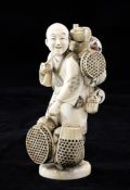 A Japanese ivory figure of a basket seller, early 20th century, holding a tobacco pipe in his right