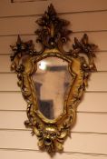 A pair of 20th century Italian carved giltwood cartouche shaped wall mirrors, each with a floral C