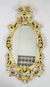 A mid 18th century carved giltwood oval wall mirror, with pierced C scroll and floral frame, L.3ft