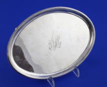 A George III silver oval teapot stand, with reeded border and engraved monogram, on four scroll