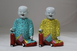 Two Chinese famille rose enamelled jostick holders, modelled as seated boys, Jiaqing period, each