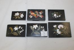 A collection of six Derbyshire black marble rectangular paperweights, each inlaid with coloured