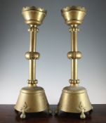 A large pair of late Victorian gothic brass candlesticks, the sconces with shaped border and knop
