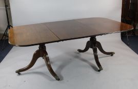 A George III style mahogany extending twin pillar dining table, with rounded ends, on downswept