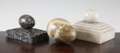 A white and grey veined marble egg shaped paperweight, on a stepped rectangular base, together