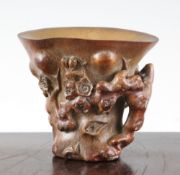 A Chinese bamboo libation cup, of rhinoceros horn form, carved in relief and open work with prunus