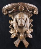 A late 19th century Black Forest carved wall bracket, decorated with a dog`s head, oak leaves and