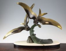 An Art Deco green and black patinated metal group of seagulls on the crest of a wave, on an oval