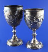 Two similar Victorian silver trophy cups, both embossed with hunting scenes, on turned stems and