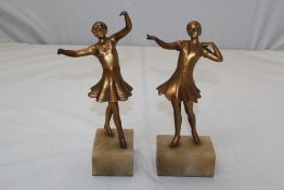 A pair of Art Deco gilt painted metal figures of dancing females, on brown plinth onyx bases, 10in.