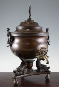 A Regency bronze samovar, with figural swing handles, three dolphin supports and triparte base, 19.