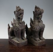 A pair of Burmese carved hardwood seated lion-dog figures, 38.5cm.