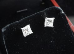A pair of 18ct white gold and princess cut solitaire diamond ear studs, each with an individual