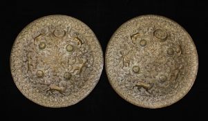 A near pair of Indian embossed brass dhals, each with four raised bosses decorated with lions,