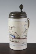 A German faience tankard, 18th century, with pewter mounted hinged cover, painted in colours with