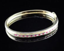 An 18ct gold, ruby and diamond set hinged bracelet.