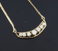 A 14ct gold and diamond set crescent shaped pendant, set with seven graduated diamonds, on a fine