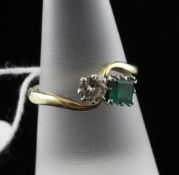 An 18ct gold, emerald and diamond crossover ring, with round cut diamond and square cut emerald,