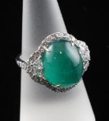 A white gold, cabochon emerald and diamond cluster ring, the oval cabochon weighing approximately