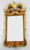 A figured walnut and carved giltwood wall mirror, the broken swan neck pediment with central