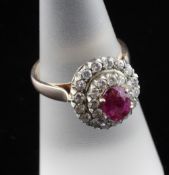 A gold, ruby and diamond set cluster ring, of oval form, with central ruby bordered by stepped