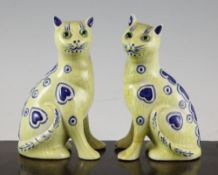 A pair of Galle style yellow glazed pottery figures of cats, each seated and decorated with blue