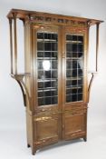 An Arts and Crafts oak bookcase, fitted a pair of lead light doors over a pair of cupboard doors,