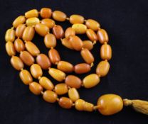A single strand graduated amber bead necklace, with tassel terminal, gross weight 82 grams, 39in.