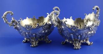 An ornate pair of Edwardian embossed silver two handled fruit bowls by Mappin & Webb, with flying