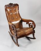 A Victorian mahogany and brown leather rocking chair, with button back and padded arm rests, on