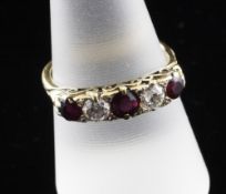 A gold and five stone ruby and diamond half hoop ring, with carved scroll setting, size Q.