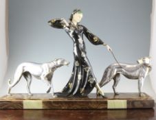 An Art Deco patinated figure of a lady, with ivorine face, accompanied by two attendant dogs, on a