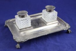 An Edwardian silver desk stand, of rectangular form, with shell and gadrooned border and two mounted