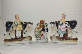 A pair of Staffordshire groups of a farmer and milkmaid with cows, and another group, the cow groups