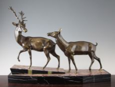 A French Art Deco patinated metal group of a stag and doe, on a shaped marble base, 22in.