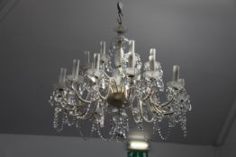 A 20th century glass multi-light chandelier, with facet decorated stem and twenty four scrolling