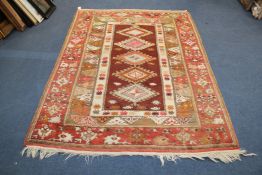 A Caucasian rug, with four central diamond motifs on a chocolate ground, with three broad row