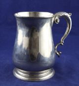 A large George II silver mug, of plain baluster form, with acanthus leaf capped scroll handle,