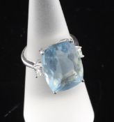 An 18ct white gold, aquamarine and diamond set dress ring, the cushion cut aquamarine flanked by two