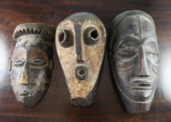 A West African carved mask, probably Liberian with traces of white pigment, together with two