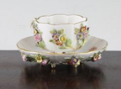 A Meissen flower encrusted small tea cup and saucer, late 19th century, with stump feet to both
