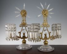 A pair of 19th century ormolu and cut glass candelabra, surmounted by sunburst mask motifs set