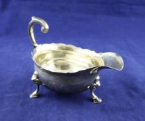 A mid 18th century silver sauceboat, with engraved monogram and armorial, on hoof feet with flying