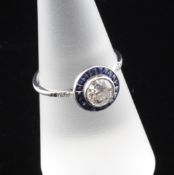 A white gold, sapphire and diamond set target ring, the central diamond weighing 0.67ct, size N.