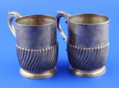 A pair of late Victorian demi spiral fluted silver mugs, with acanthus leaf capped handles and